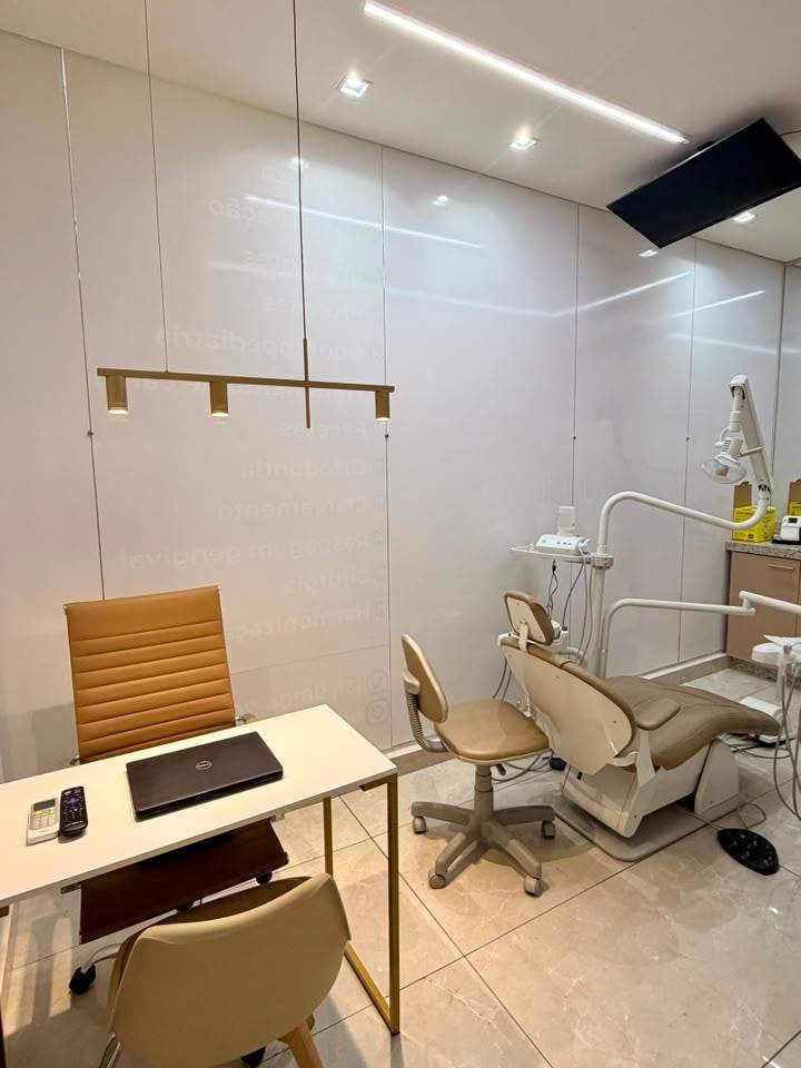 Ambiente de atendimento da Essence com mesa de conversa e cadeira odontológica ao fundo